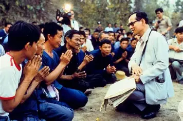 Thailand England Untold Truths article image: King Bhumibol Adulyadej speaking with Thai villagers during a royal tour.