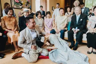 Traditional Thai wedding ceremony: the bride prostrates before her kneeling groom as family and friends watch.