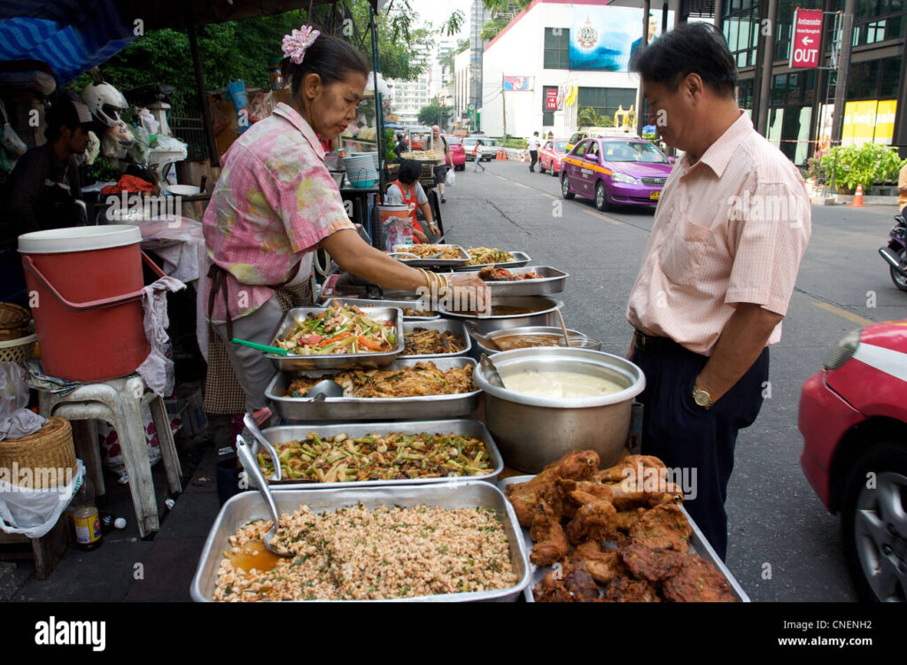A street vendor in Chiang Mai serving a customer with a selection of freshly cooked foods