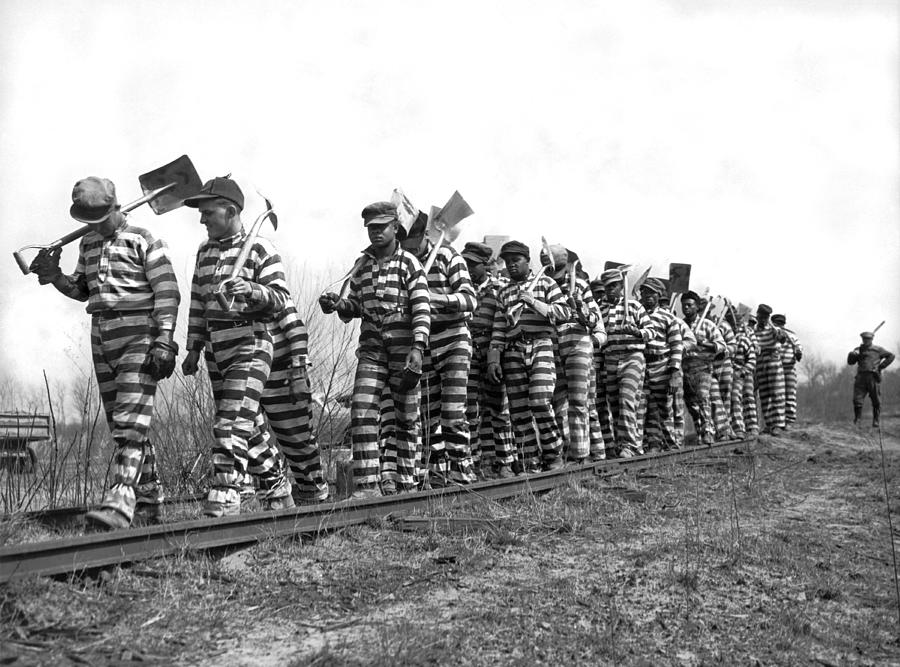Prisoners in chains walking along a railway line to their work assignment