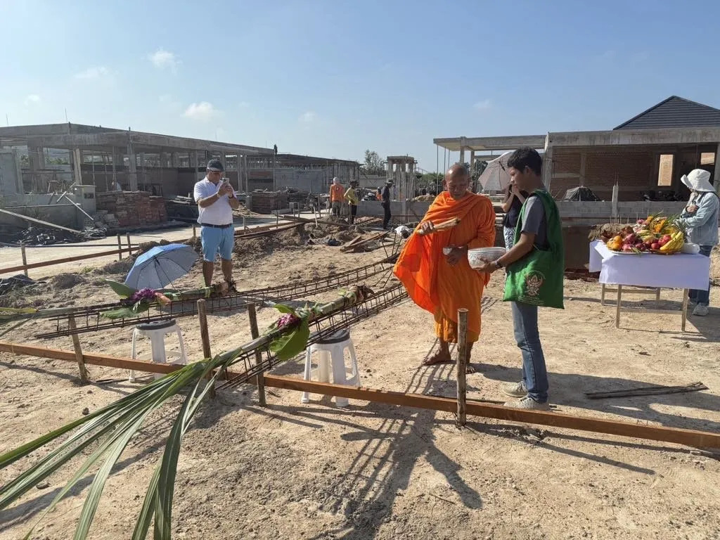 A monk officiating at a New House Ceremony, before the build commences He's sprinkling holy water.