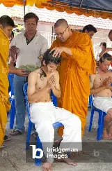 Before the ordination ceremony, a Thai man has his head shaved by a senior Buddhist monk