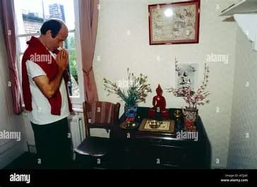 A man waiing a Buddha image in the "Shrine Room" of a typical middle-class Thai home. 